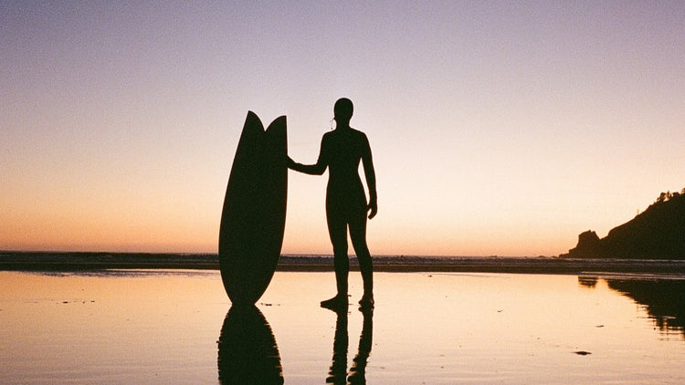 Surfer watching the sunset while wearing the Billabong Women's Synergy Natural Wetsuit